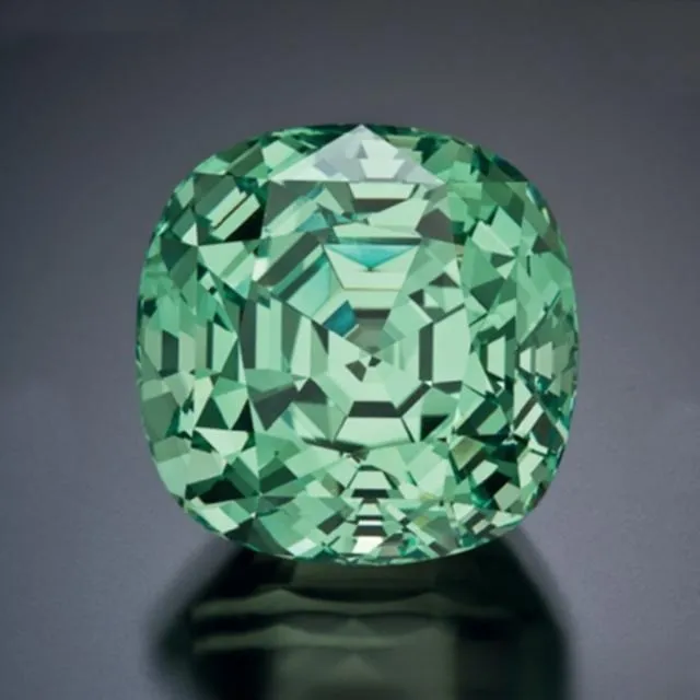 An image of a loose vanadium chrysoberyl gemstone. The gem has a vibrant green color, similar to a green apple, and is colored by the element vanadium. This variety is very rare and expensive on the market.