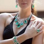 Elegant woman wearing vibrant green emerald jewelry, showcasing rings, necklaces, and earrings in a stylish ensemble