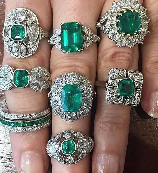 Hand showcasing different emerald gemstone rings, displaying a variety of green shades and ring styles in this Emerald Buying Guide