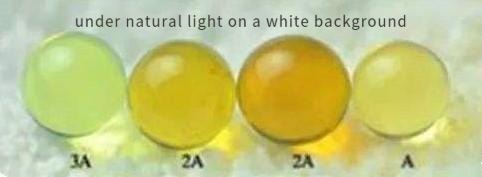 Blue amber on a white or light background, with yellow and golden light reflections masking its subtle blue glow.