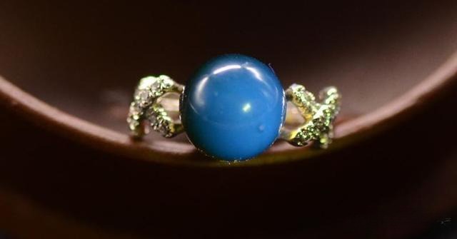 Blue amber gemstone set in a ring, highlighting its natural beauty and color.