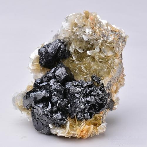 Cassiterite gemstone associated with mica, black portions representing cassiterite, showcasing natural high-dispersion potential