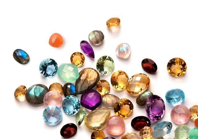 Collection of colored gemstones including ruby, sapphire, emerald, and tourmaline showing natural hues and brilliance.