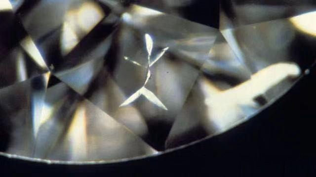 Close-up of a diamond showing feather inclusion resembling a tiny figure, one of the diamond cracks and inclusions.