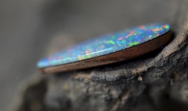 Side view of doublet opal showing the glued layer junction between the opal slice and base – Gemstone Jewelry Buying Tips.