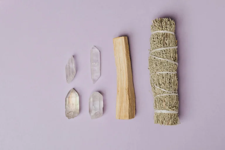 Flat lay of various healing crystals and a sage smudge stick arranged for spiritual cleansing and energy clearing.