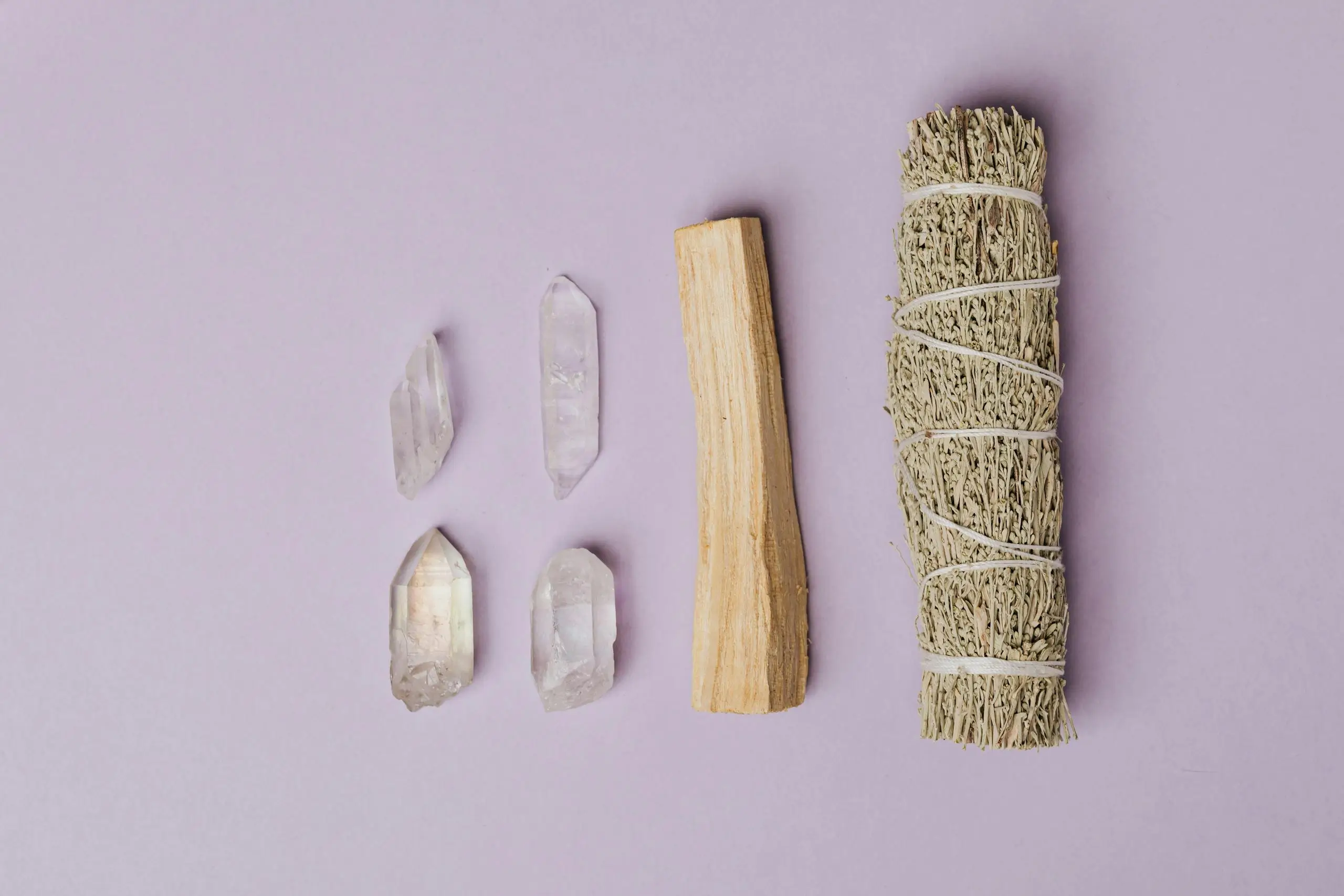 Flat lay of various healing crystals and a sage smudge stick arranged for spiritual cleansing and energy clearing.