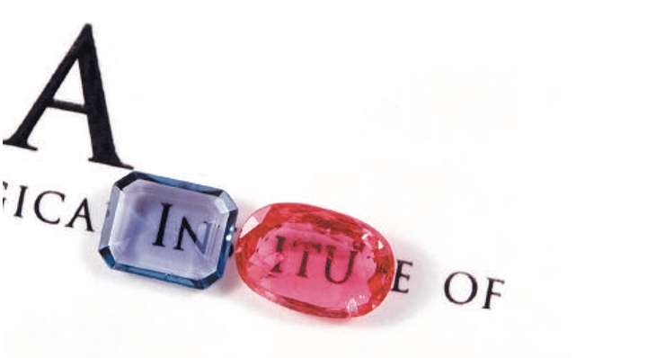 Two windowed gemstones placed face down on printed text showing visible letters through the shallow pavilion cut, making the stones appear thinner than usual.