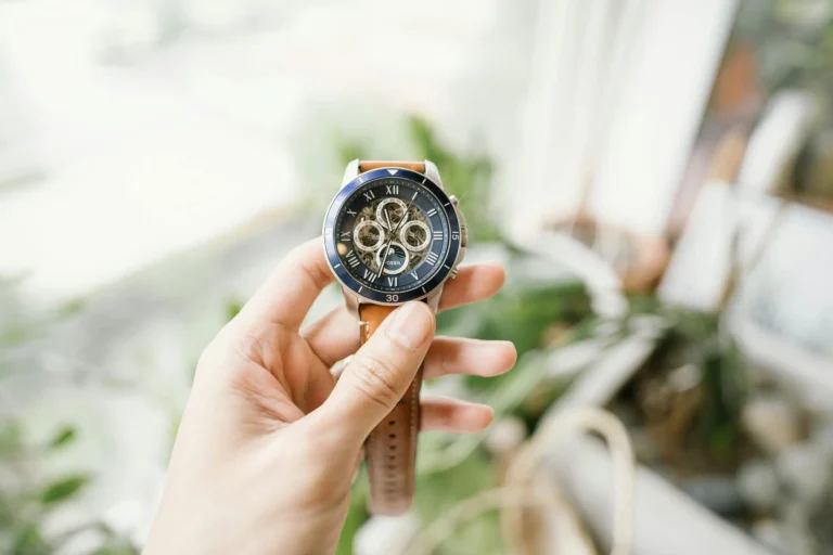 A hand holding a luxury wristwatch with intricate gears, symbolizing the timeless craftsmanship of wood marquetry in watchmaking.