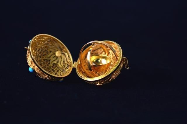 Handcrafted silver gilt perfume ball opened to reveal intricate internal details, showcasing fine filigree work and mechanical craftsmanship