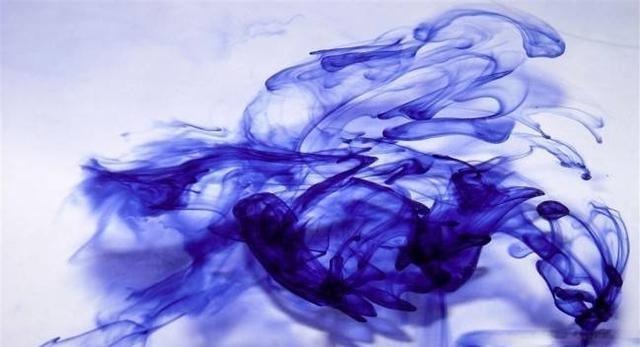 Ink dissolving in water, leaving faint color roots as the water begins to turn blue, illustrating the gradual color evolution process.