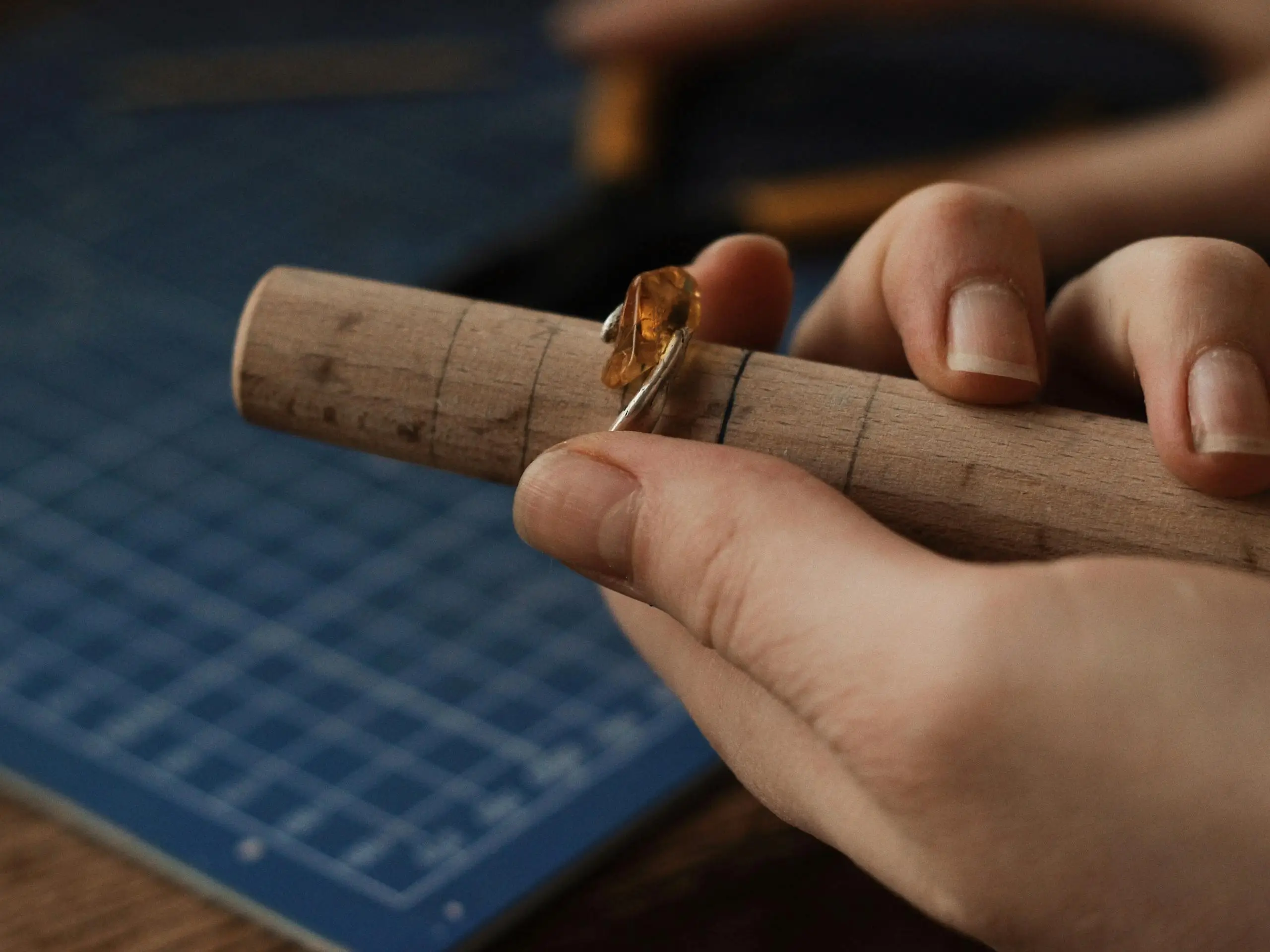 A jeweler crafting a gemstone ring on a mandrel, showcasing intricate handmade craftsmanship for the Women’s Jewelry Size Guide article.