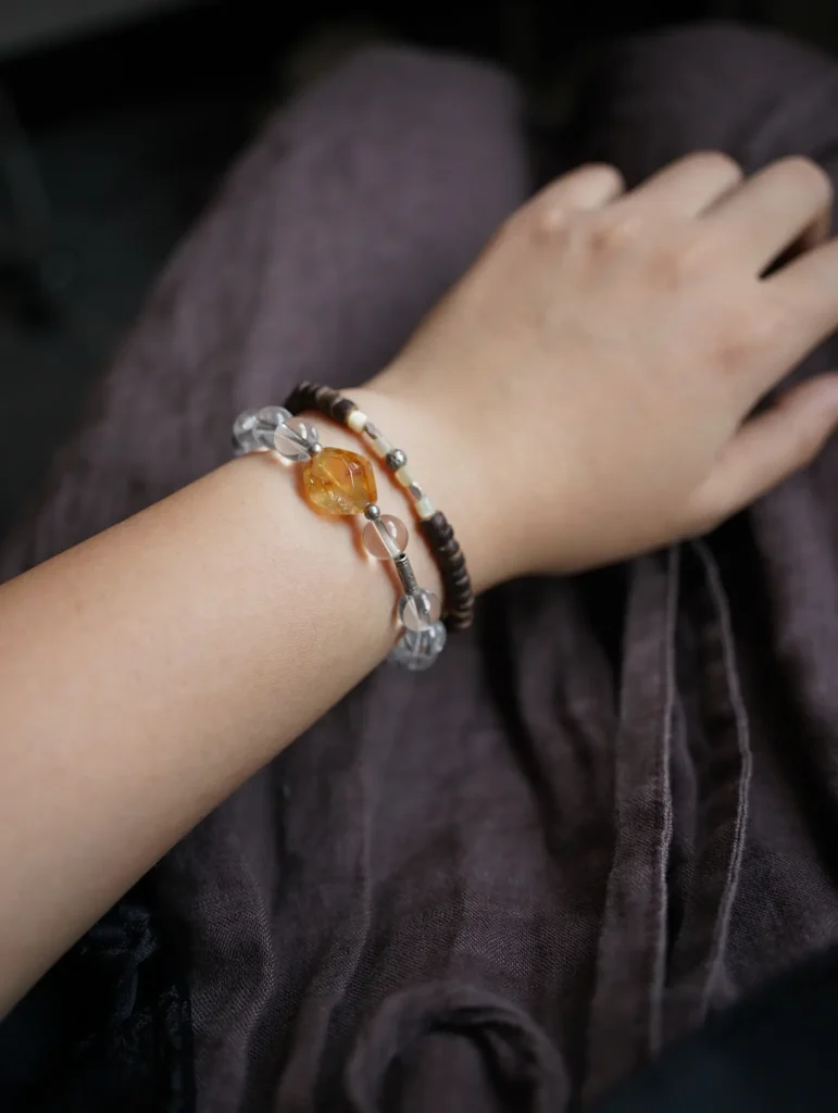 Light-colored crystal bracelet stacked with a dark bracelet for stylish layering.