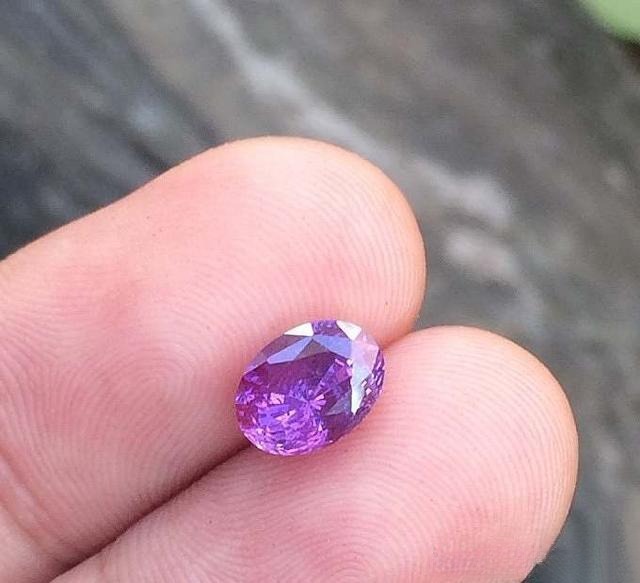 Hand holding an oval-shaped Madagascar pink sapphire