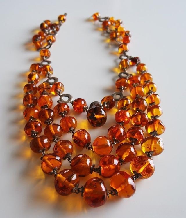 Multi-layer necklace with amber beads in varying shades and sizes, showcasing craftsmanship and elegant layered design.