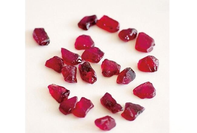 Natural ruby rough stones showing uneven length, width, and depth proportions; some are wide and flat with little thickness, others are deep and narrow, rarely perfectly shaped.