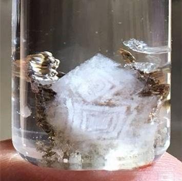 Close-up of quartz crystal showing concentric and geometric inclusions resembling tree rings, traditional Chinese patterns, and misty mountain landscapes
