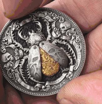 Hand holding Roman Booteen’s mechanical beetle coin, showcasing the engraved details and artistic craftsmanship.