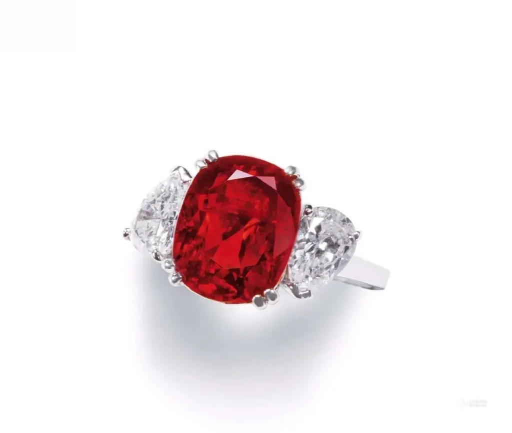 A fine jewelry ring featuring a vivid red gemstone center stone surrounded by sparkling diamonds.