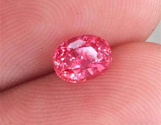 Hand holding an oval Sri Lankan unheated Padparadscha sapphire
