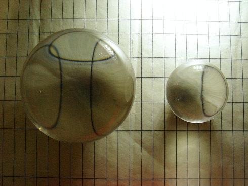 Two quartz crystals of different sizes placed on a hair to demonstrate the double refraction test. Only the larger crystal may show double images; smaller crystals do not reveal birefringence.