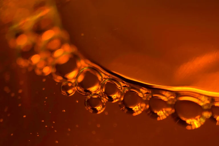 Close-up of vibrant amber liquid with bubbles, serving as the featured background image for Jewea' real amber identification guide.