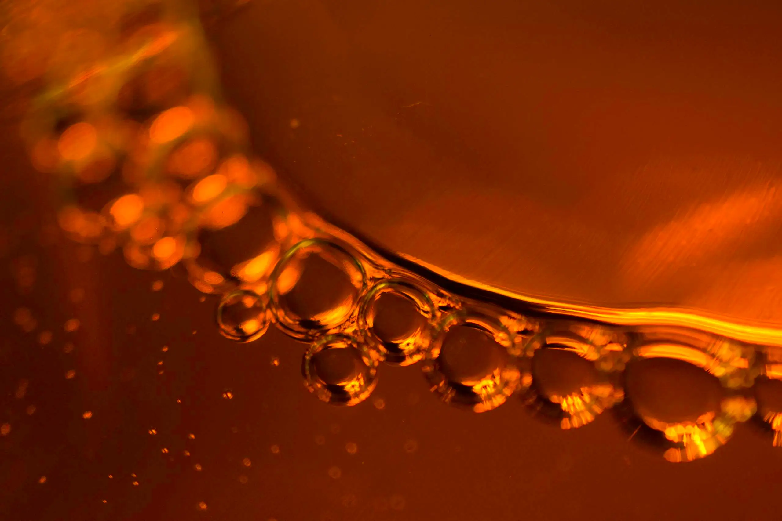 Close-up of vibrant amber liquid with bubbles, serving as the featured background image for Jewea' real amber identification guide.
