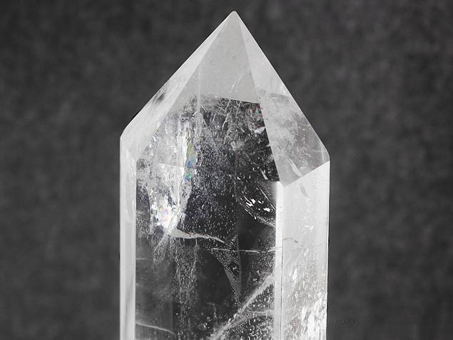 White natural quartz crystal with tiny mineral needles, gas bubbles, and growth pattern inclusions.