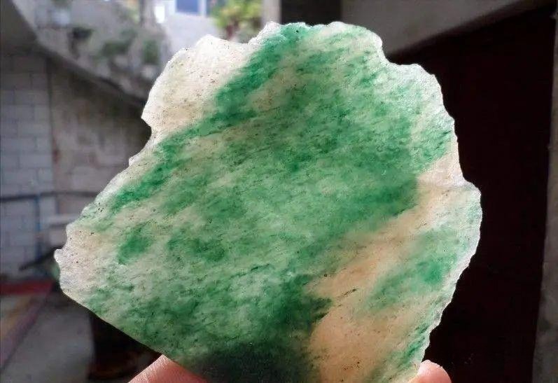 Dushan Jade sample showing uneven color distribution, where darker green dots and 'color roots' disrupt the background green, unlike the smooth blend in quality Hetian Jade.