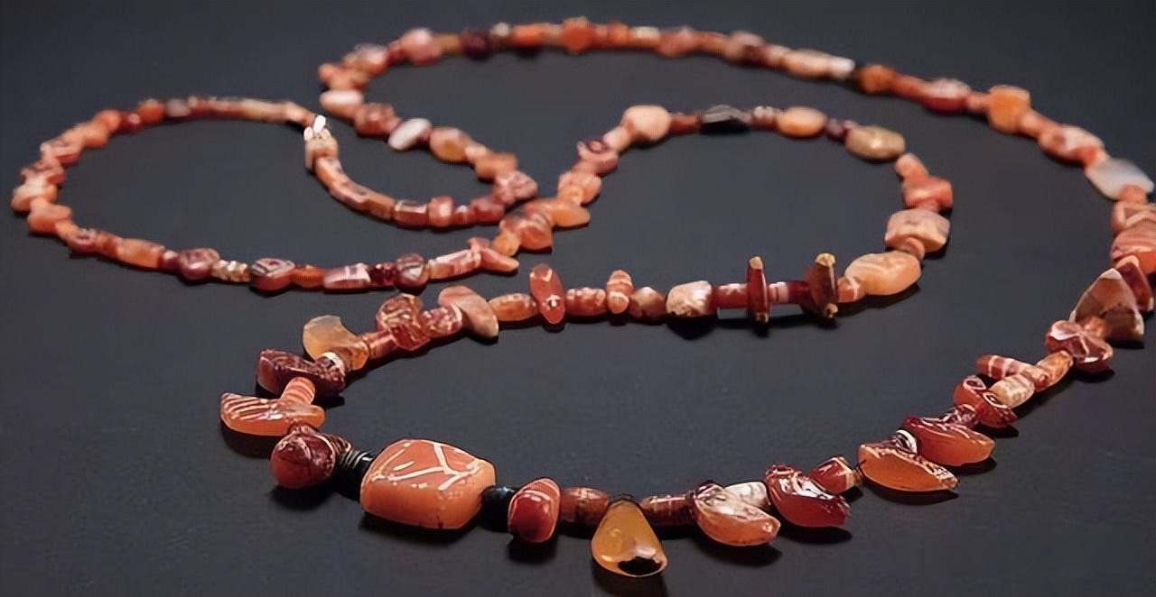 A necklace featuring etched flower beads with white patterns, part of Indus Valley jewelry symbolizing social status and religious significance in the Harappan civilization.