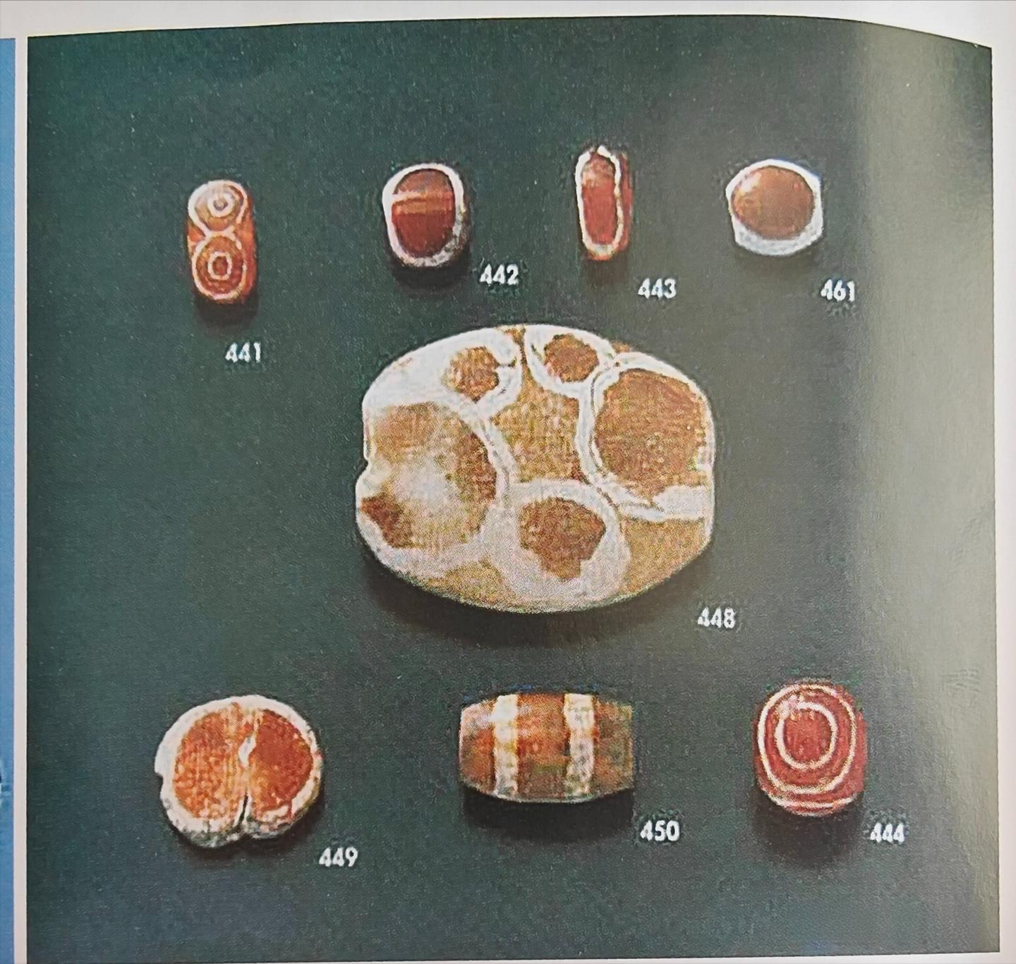 Beads with black and white floral patterns created using the etching technique, part of Indus Valley jewelry showcasing artistic contrast and craftsmanship.