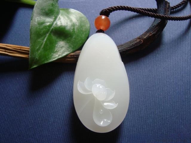 Hand-carved white jade lotus pendant featuring delicate craftsmanship and elegant traditional design.