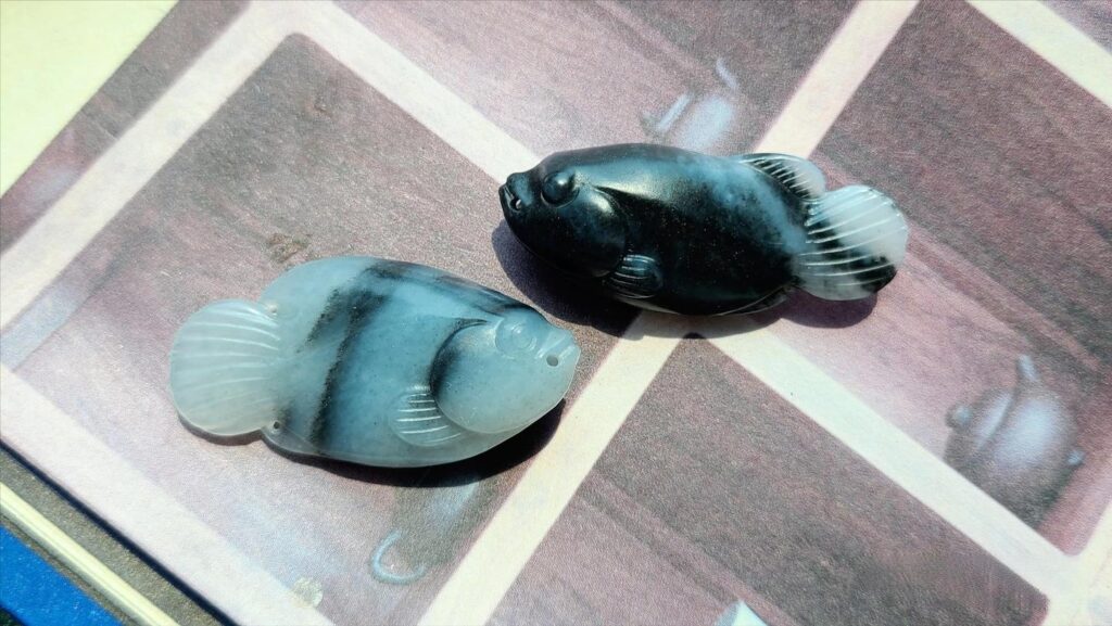An authentic Hetian Jade 'Qinghua' (Black-and-White) carving of double fish. This material is visually similar to the black and white crystalline Jinsi Jade, necessitating careful authentication.