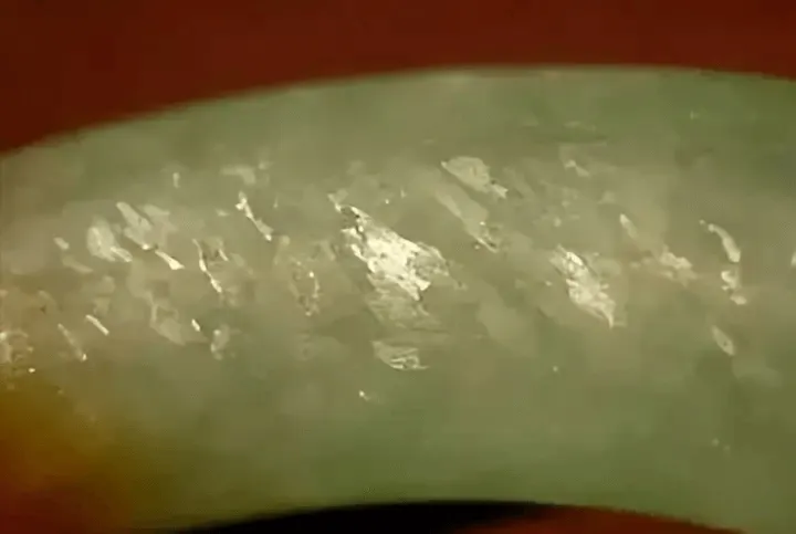 Jewea jadeite bangle magnified view, highlighting flywing texture in white granular stone areas