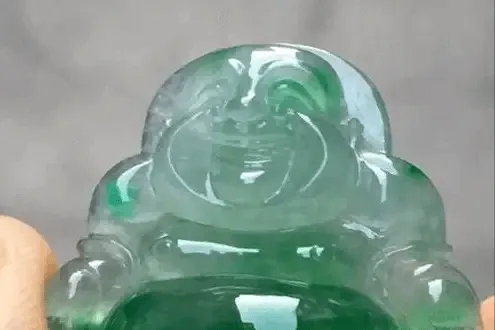 Jewea jadeite Buddha pendant with off-color green tones showing hints of blue, black, and uneven color, see Jadeite Buying Guide