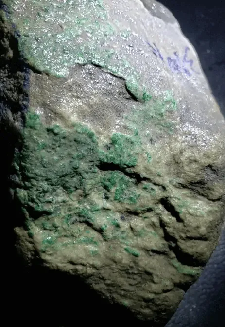 Jadeite rough showing spruce-green patterns on the skin, indicating internal color distribution and variations.