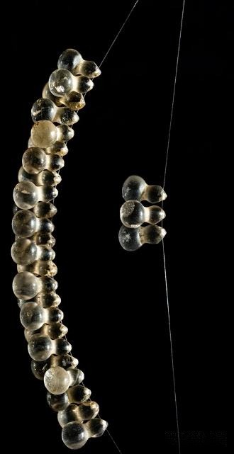 A Northern Song crystal necklace composed of 66 beads and a larger central bead, retaining delicate feather-like patterns despite centuries of wear, reflecting the Song dynasty’s aesthetic of ethereal beauty.