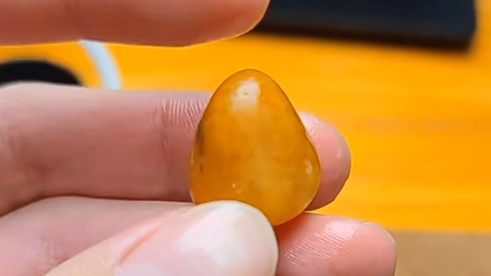 Close-up photograph comparing rough quartzite stone used to imitate Hetian Jade seed material by showing fake river-worn texture and pores.