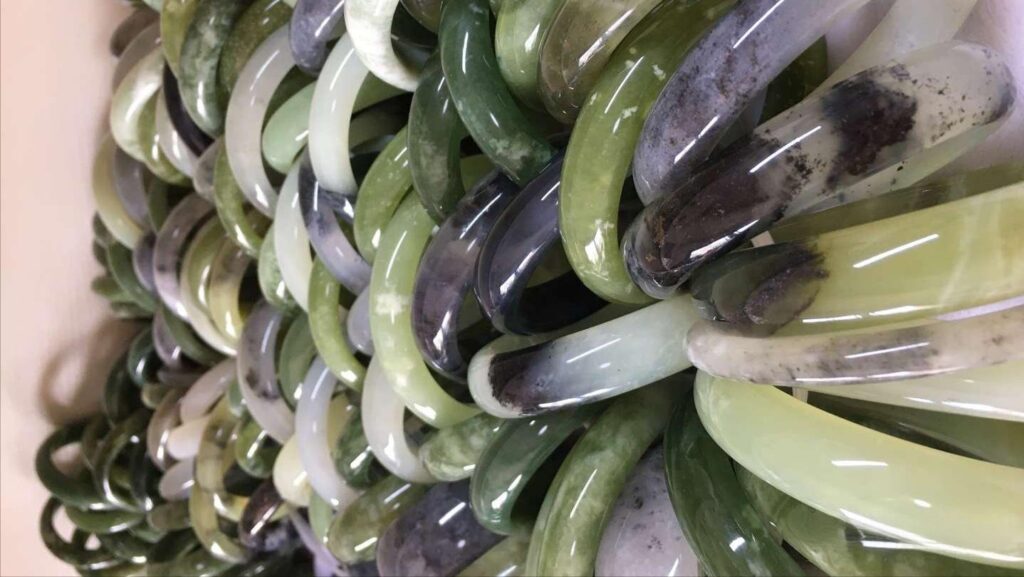 A large collection of various Serpentine Jade (Xiuyu) bangles, displaying the material's range of color and texture.