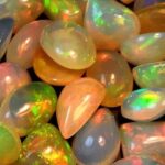 A close-up collection of vibrant opals exhibiting intense play-of-color (iridescence) and fire, showcasing the gem's natural splendor when fully hydrated.