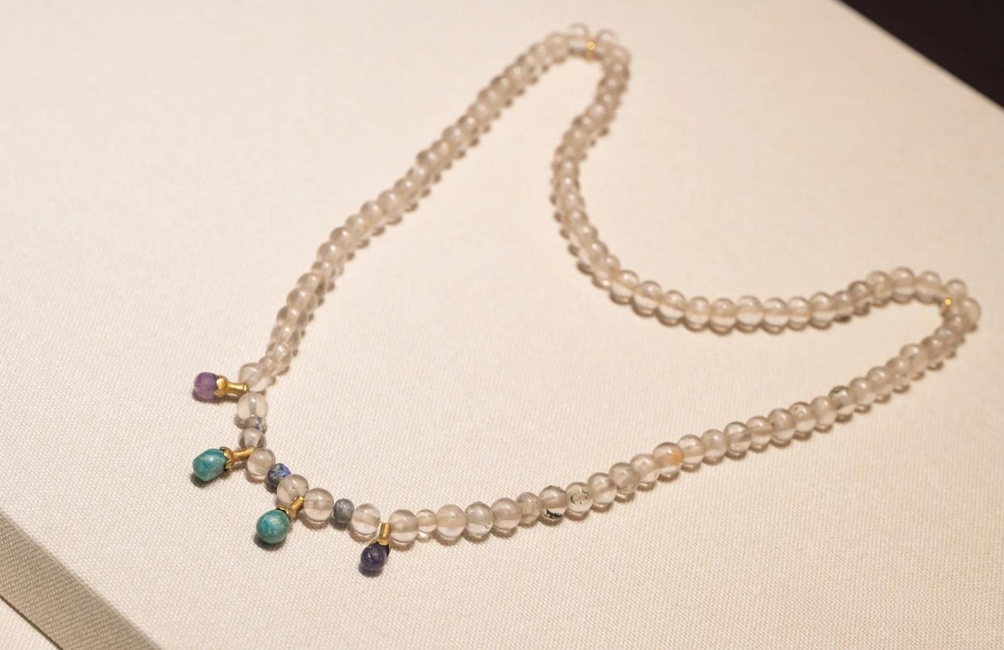 A Tang Dynasty crystal necklace from the Mi Tomb in Xi’an, composed of 92 crystal beads, 3 blue glass beads, 2 amethyst, 2 turquoise pendants, and 4 gold connectors, showcasing the Tang era’s pursuit of brilliance and elegance.