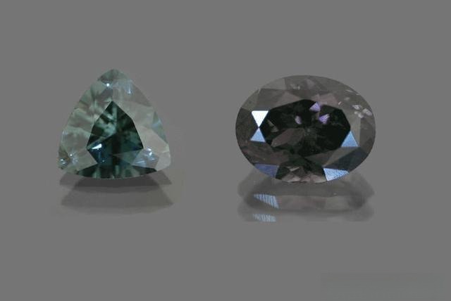 Two Sapphirine gemstones on the same background, one bluish-green and the other with a strong gray undertone