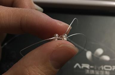 Binding the middle and bottom pearl rings; the key is staggering the knots to prevent alignment and ensuring a firm seal.