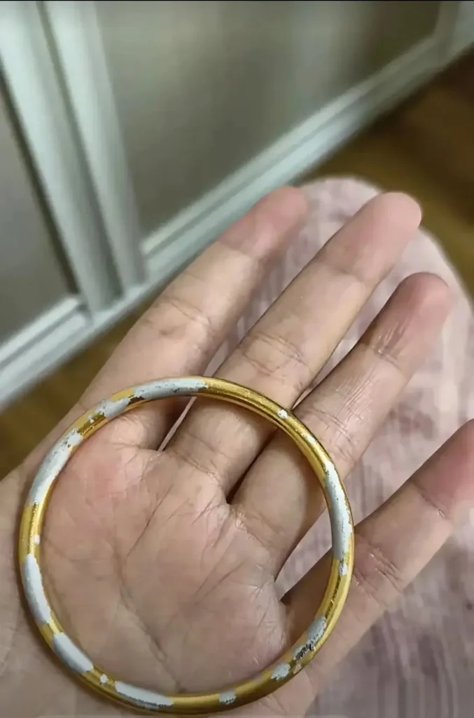 A faded gold-plated bangle showing base metal underneath.