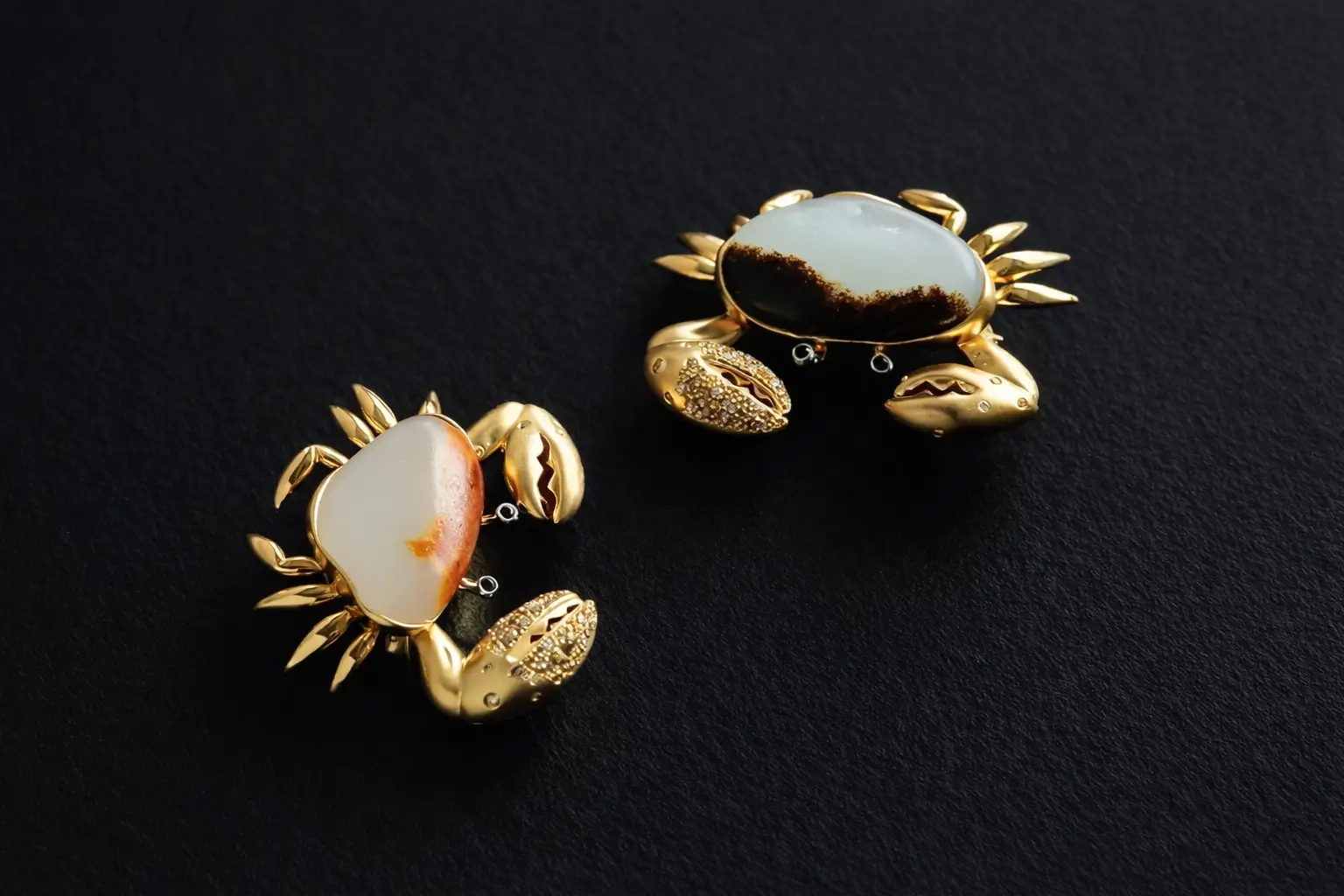 Two vintage gold-inlaid jade crabs with intricate filigree details.