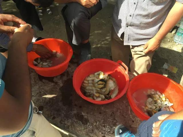 A Uighur adaxi (seller) presenting rough Hetian Ziyu stones for sale at a small, informal stall in the Mariyan market.