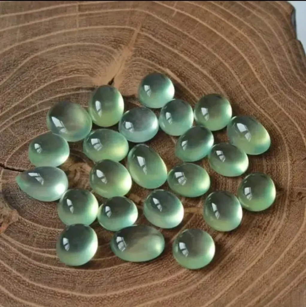 A collection of Prehnite cabochons showing a delicate, translucent texture and a soft, pleasing green color.
