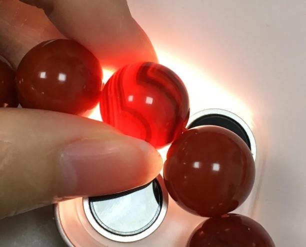 Checking natural color patterns and texture of Southern Red Agate under bright light at home.