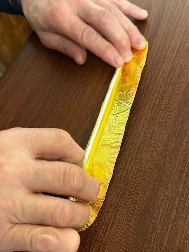 A craftsman fusing a thick gold sheet to a silver bangle.