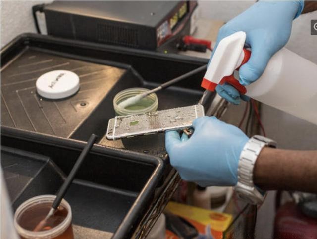 A technician applying gold plating to an iPhone.